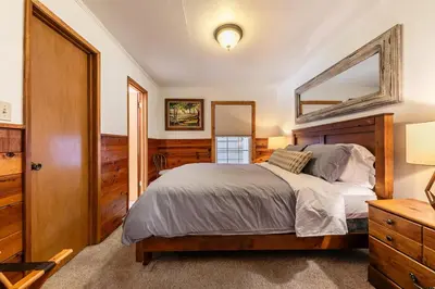 a bedroom with a large bed and a mirror at Reflections Lakeview Cabin - Private Beach Access, Hot Tub & Buoy! in Carnelian Bay