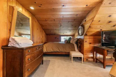 a bedroom in a log cabin with a bed and a desk at Reflections Lakeview Cabin - Private Beach Access, Hot Tub & Buoy! in Carnelian Bay