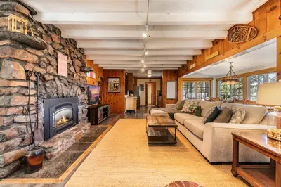 a living room with a large stone fireplace at Reflections Lakeview Cabin - Private Beach Access, Hot Tub & Buoy! in Carnelian Bay