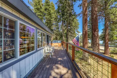 a deck with a table and chairs on a house at Reflections Lakeview Cabin - Private Beach Access, Hot Tub & Buoy! in Carnelian Bay