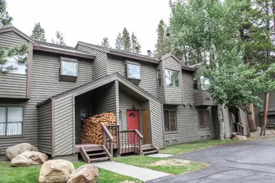 a house with a red door and a pile of logs at Forest Creek #16 condo in Mammoth Lakes