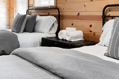 two beds in a room with wooden walls at The Pine Loft | Yosemite in North Fork