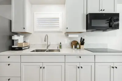 a white kitchen with a sink and a microwave at Mountain View Apartment in North Fork