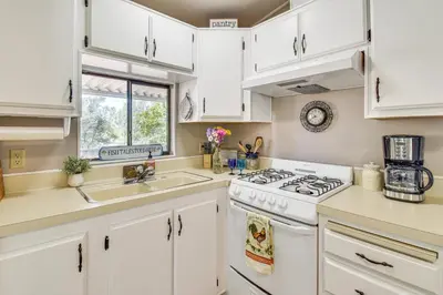 a kitchen with white cabinets and a stove and sink at La Grange Home with Covered Patio and Gas Grill! in La Grange