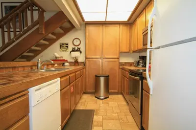 a kitchen with wooden cabinets and a white refrigerator at Mountainback 68 2 bedroom with loft in Mammoth Lakes