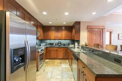 a kitchen with wooden cabinets and a stainless steel refrigerator at Big Horn Lodge 208 by East West Hospitality in Truckee