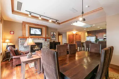 a dining room and living room with a table and a fireplace at Big Horn Lodge 208 by East West Hospitality in Truckee