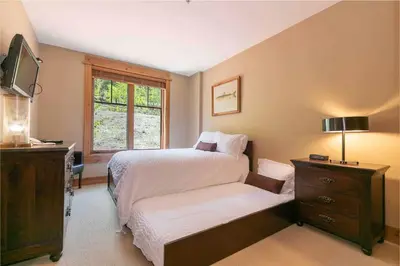 a bedroom with a bed and a dresser and a window at Big Horn Lodge 208 by East West Hospitality in Truckee