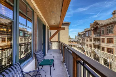 a balcony with two chairs and a view of buildings at Big Horn Lodge 301 by East West Hospitality in Truckee