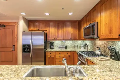a kitchen with wooden cabinets and a stainless steel refrigerator at Big Horn Lodge 301 by East West Hospitality in Truckee