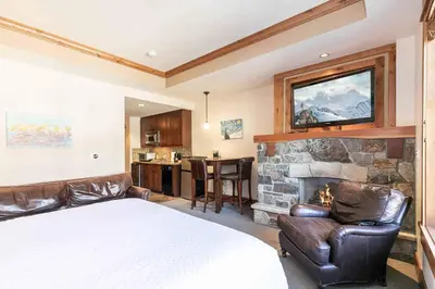 a bedroom with a bed and a stone fireplace at Big Horn Lodge 305 by East West Hospitality in Truckee