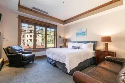 a bedroom with a bed and a chair and a window at Big Horn Lodge 305 by East West Hospitality in Truckee