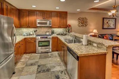 a kitchen with wooden cabinets and stainless steel appliances at Big Horn Lodge 309 by East West Hospitality in Truckee