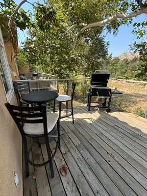 a table and chairs on a deck with a piano at Sequoia River Front Cabins in Three Rivers
