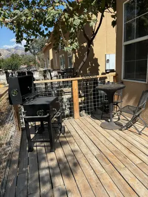 a wooden deck with a grill and a table on it at Sequoia River Front Cabins in Three Rivers