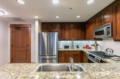 a kitchen with wooden cabinets and a stainless steel refrigerator at Big Horn Lodge 409 by East West Hospitality in Truckee
