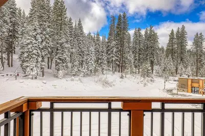 a wooden deck with snow covered trees in the background at Big Horn Lodge 404 by East West Hospitality in Truckee
