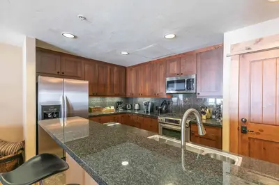 a kitchen with wooden cabinets and a stainless steel refrigerator at Big Horn Lodge 310 by East West Hospitality in Truckee
