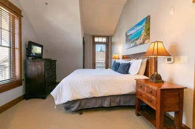 a bedroom with a bed and a dresser and a television at Big Horn Lodge 501 by East West Hospitality in Truckee