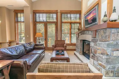 a living room with a couch and a stone fireplace at Big Horn Lodge 510 by East West Hospitality in Truckee