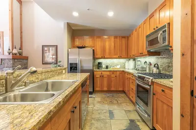 a kitchen with wooden cabinets and a stainless steel refrigerator at Big Horn Lodge 510 by East West Hospitality in Truckee