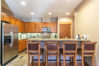a kitchen with wooden cabinets and a bar with bar stools at Big Horn Lodge 510 by East West Hospitality in Truckee