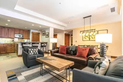 a living room with couches and a table and a kitchen at Big Horn Lodge 410 by East West Hospitality in Truckee