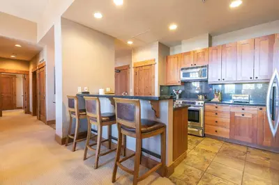 a kitchen with wooden cabinets and a island with bar stools at Big Horn Lodge 511 by East West Hospitality in Truckee