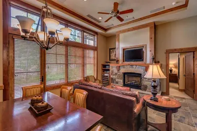 a living room with a couch and a table and a fireplace at Catamount Lodge 103 by East West Hospitality in Truckee