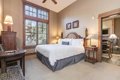 a bedroom with a bed and a desk and a window at Catamount Lodge 103 by East West Hospitality in Truckee