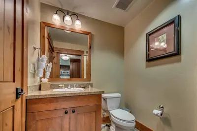 a bathroom with a toilet and a sink and a mirror at Catamount Lodge 103 by East West Hospitality in Truckee