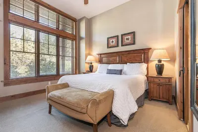 a bedroom with a large bed and a chair at Catamount Lodge 103B by East West Hospitality in Truckee