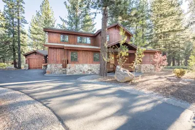 a house in the woods with a driveway at Caleb Drive 12802 by East West Hospitality in Truckee