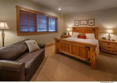 a bedroom with a bed and a leather couch at Caleb Drive 12802 by East West Hospitality in Truckee