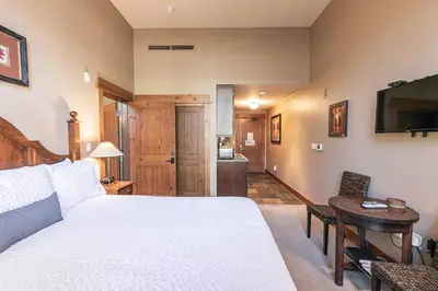 a bedroom with a bed and a table and a television at Catamount Lodge 103A by East West Hospitality in Truckee
