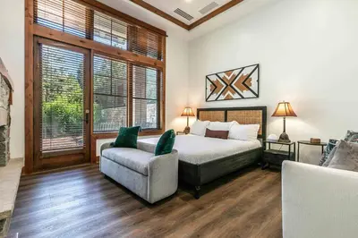 a bedroom with a bed and a chair and windows at Catamount Lodge 105 by East West Hospitality in Truckee