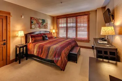 a bedroom with a bed and a desk and a television at Catamount Lodge 204 by East West Hospitality in Truckee