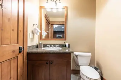a bathroom with a toilet and a sink and a mirror at Catamount Lodge 201 by East West Hospitality in Truckee