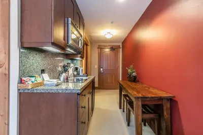 a kitchen with a counter and a wooden table at Catamount Lodge 201 by East West Hospitality in Truckee
