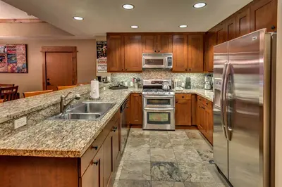 a kitchen with wooden cabinets and stainless steel appliances at Catamount Lodge 204B by East West Hospitality in Truckee