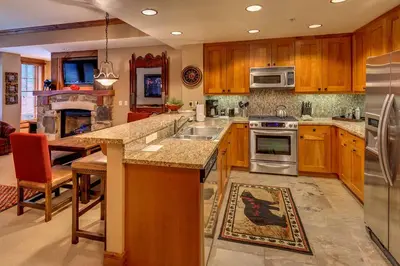a kitchen with wooden cabinets and stainless steel appliances at Catamount Lodge 211 by East West Hospitality in Truckee
