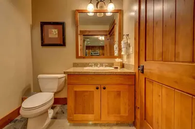 a bathroom with a toilet and a sink and a mirror at Catamount Lodge 206 by East West Hospitality in Truckee
