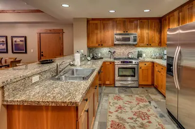 a kitchen with wooden cabinets and a stainless steel refrigerator at Catamount Lodge 206 by East West Hospitality in Truckee