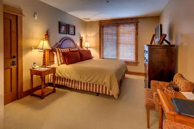 a bedroom with a bed and a table and a chair at Catamount Lodge 206 by East West Hospitality in Truckee