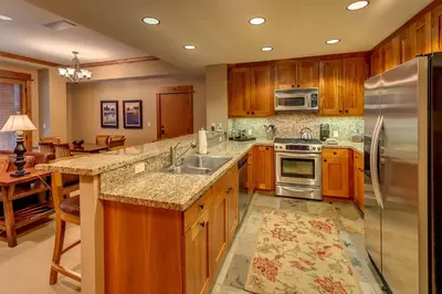 a kitchen with wooden cabinets and a stainless steel refrigerator at Catamount Lodge 206B by East West Hospitality in Truckee