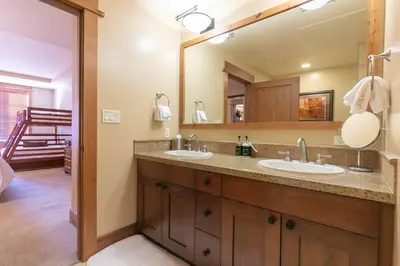 a bathroom with two sinks and a large mirror at Catamount Lodge 308 by East West Hospitality in Truckee