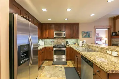 a kitchen with wooden cabinets and stainless steel appliances at Catamount Lodge 308 by East West Hospitality in Truckee