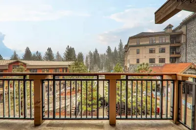 a balcony with a wooden railing and buildings at Catamount Lodge 305 by East West Hospitality in Truckee
