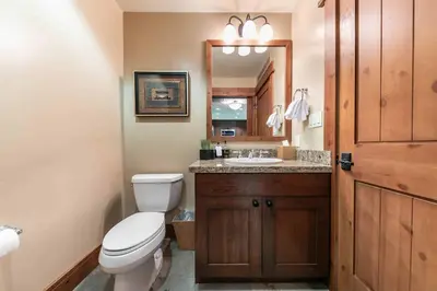 a bathroom with a toilet and a sink and a mirror at Catamount Lodge 305 by East West Hospitality in Truckee