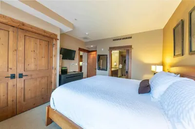 a bedroom with a large white bed and wooden cabinets at Catamount Lodge 305B by East West Hospitality in Truckee